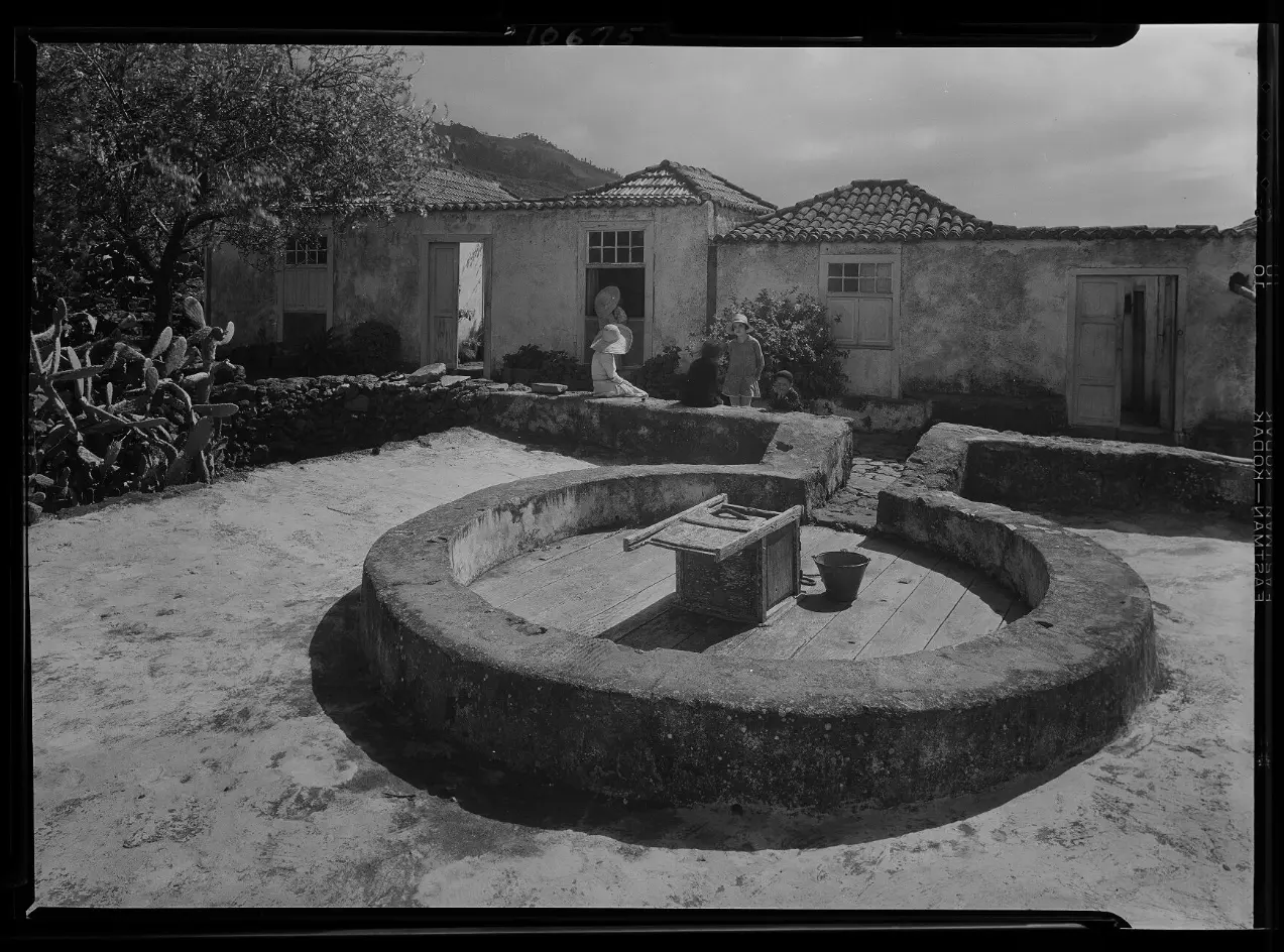 Lateral de una casa de campo, pila de piedra y niños